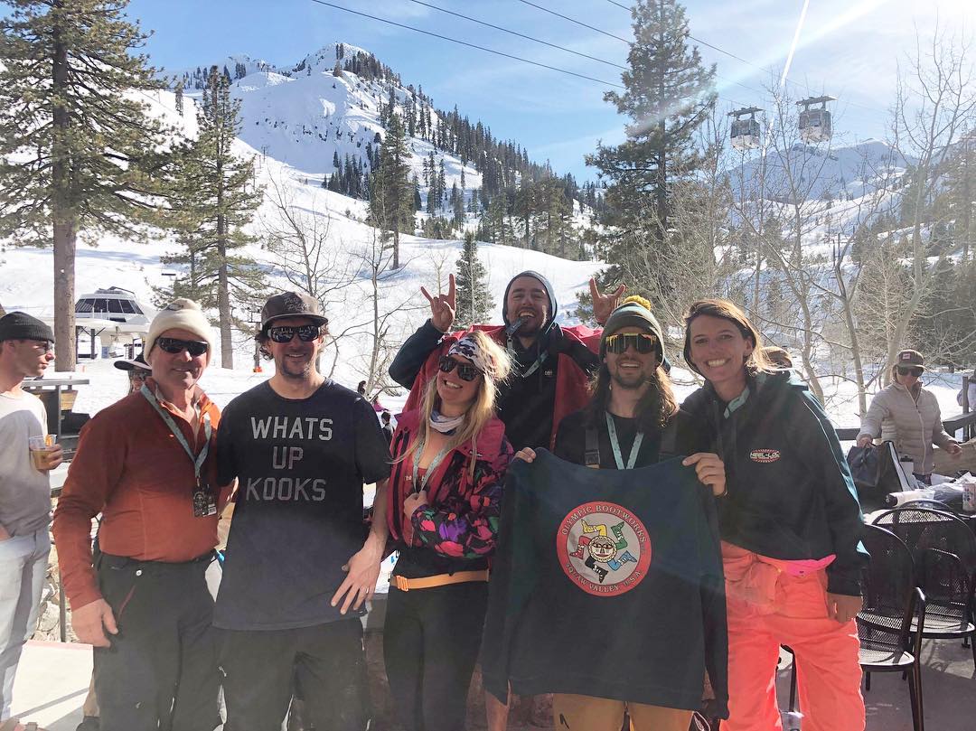 Customers on slopes holding up Olympic Bootworks t-shirt